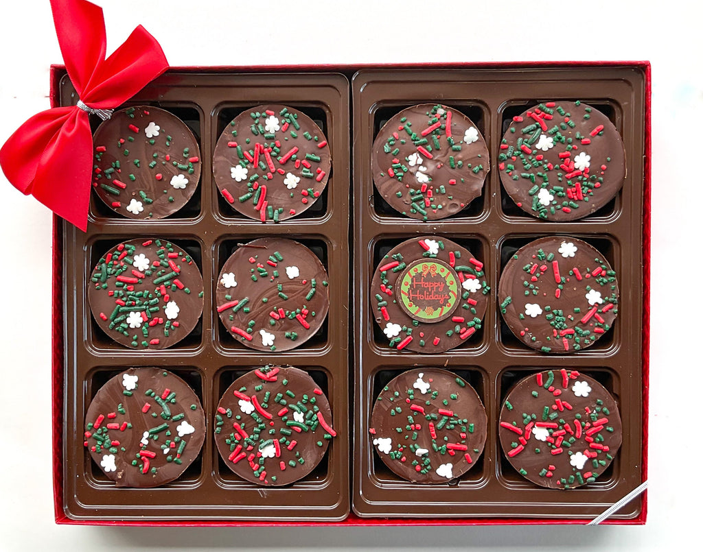 12 Milk Chooclate Covered Oreos that say "Happy Holidays" with Christmas Snowflake Sprinkles and Bow